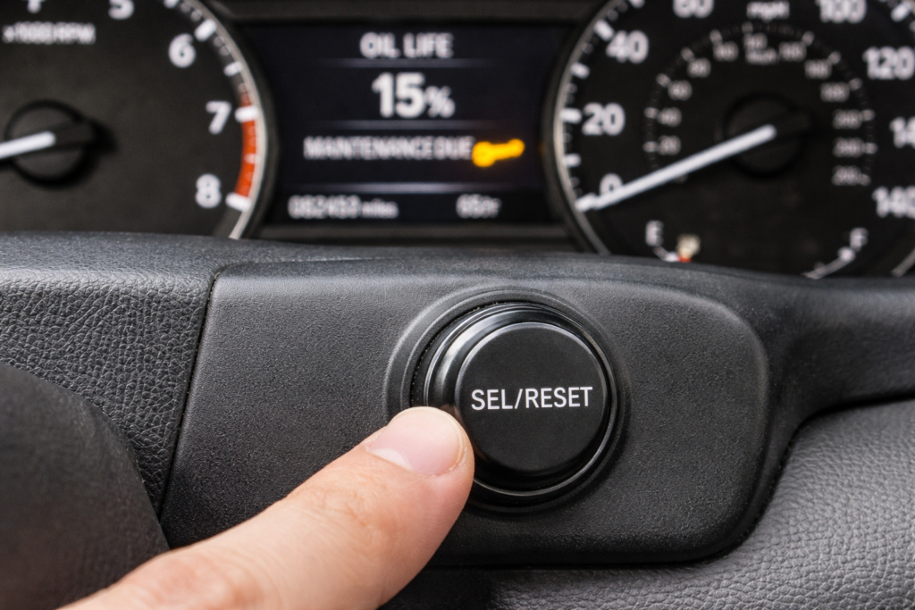 Finger pressing SELECT/RESET knob on 2006–2012 Honda Accord with oil life screen and wrench light visible in cluster
